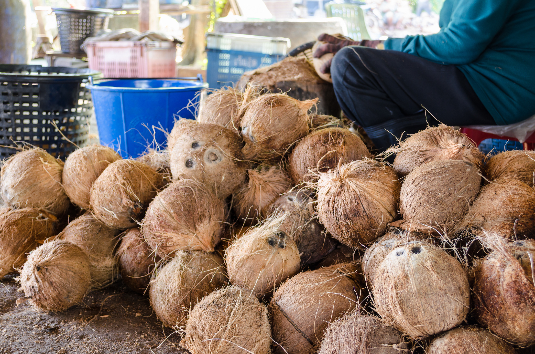 Farmer cutting coconut shell for processing agricultural products at a small factory in Thailand.